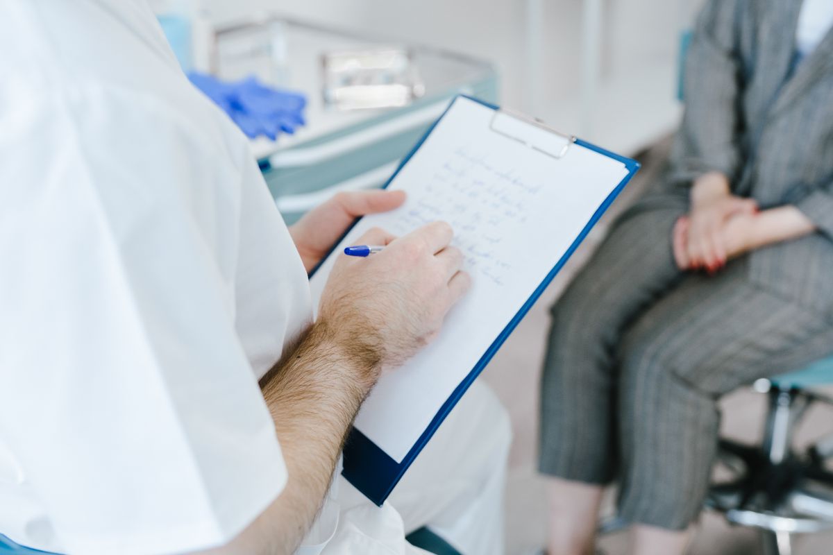 Clinician writing notes on a clipboard during a patient consultation